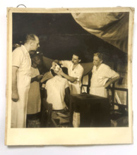 Rückseitig beschriftetes Foto von Albert Schweitzer, Dr. Percy, Dr. Lange und Pierre mit einem Patienten
